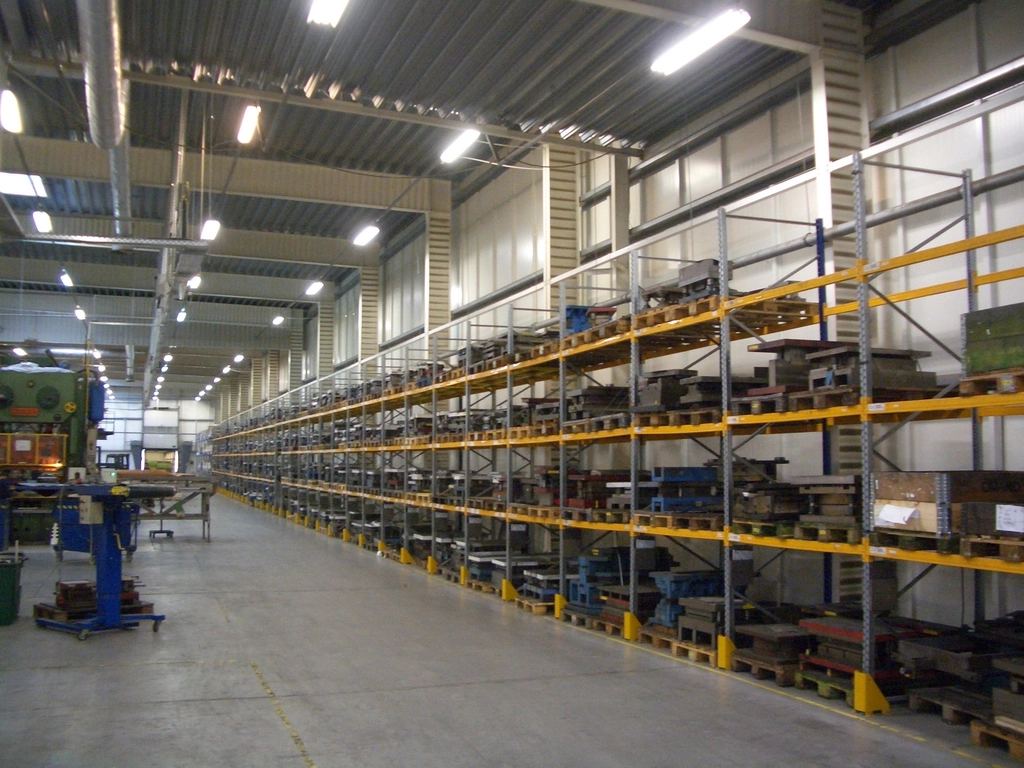 Long aisle of yellow pallet racking holding stored stock inside a bright, high-bay warehouse